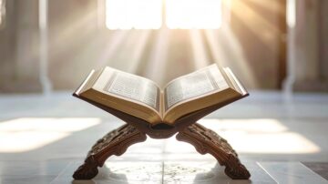 كتاب مفتوح على حامل خشبي، مع أشعة الشمس تتسلل من النوافذ خلفه، مما يخلق جوًا روحانيًا هادئًا.