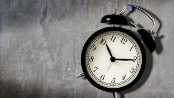 Horloge noire vintage sur un fond de mur en béton, affichant des chiffres clairs et des aiguilles indiquant 10h10.