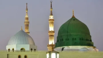 Vue de la mosquée du Prophète à Médine, mettant en avant les dômes emblématiques et les minarets illuminés au crépuscule. Les détails architecturaux soulignent l'importance religieuse et historique du site.