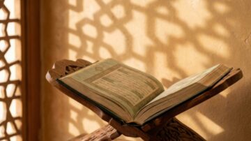 كتاب مفتوح على حامل خشبي يعبر عن مقال تعريف الورع، مع ظلال جميلة على الجدار وأجواء روحية هادئة.